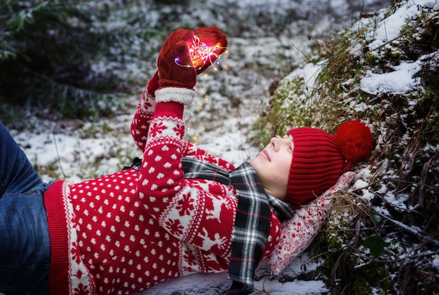 Drôle jeune homme au chapeau rouge dans la forêt d'hiver