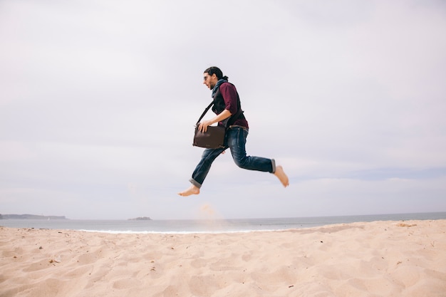 Drôle jeune homme sautant haut sur le sable