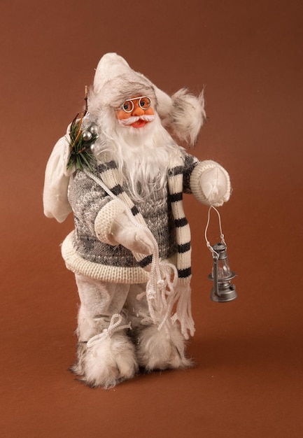 Photo un drôle de jouet du père noël avec un sac de cadeaux sur le dos et un sapin de noël à la main et un pantalon blanc