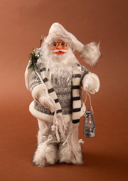 Photo un drôle de jouet du père noël avec un sac de cadeaux sur le dos et un sapin de noël à la main et un pantalon blanc