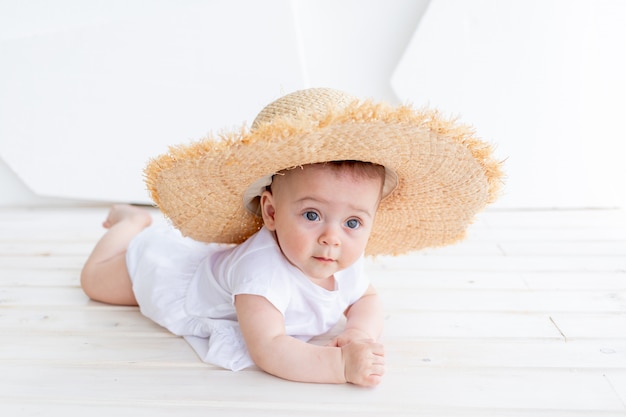 Drôle mignon enfant fille 3-4 ans tenant un chapeau de paille portant haut blanc et short en jean posant dans le parc