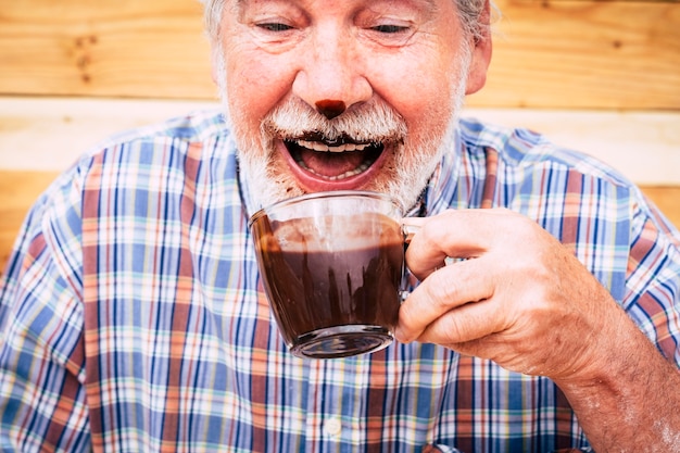 Drôle de personnes âgées heureuses caucasien vieil homme buvant du chocolat chaud et l'avoir sur le nez et la barbe - rire et s'amuser - concept d'ancienneté et style de vie à la retraite des personnes âgées joyeuses