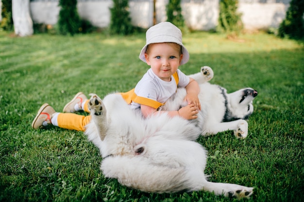 Un drôle de petit garçon posant avec le chien dans le jardin