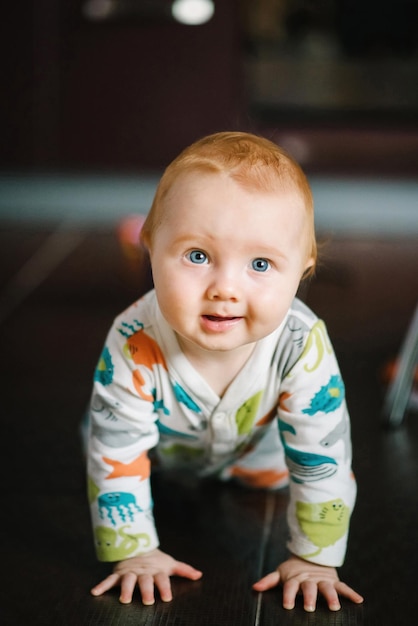 Drôle de petit garçon rampant sur le sol dans la chambre de bébé à la maison Soins de santé pour bébés et concept de famille