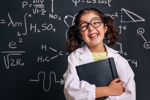 Drôle de petit scientifique riant avec un cahier