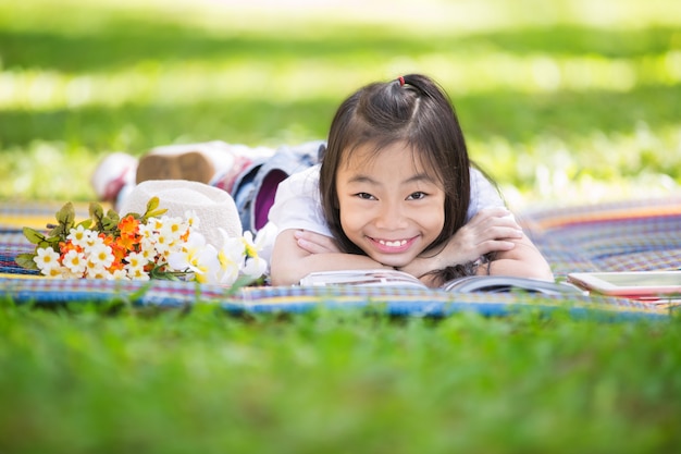 Drôle de petite fille asiatique lisant et apprenant avec tablet pc