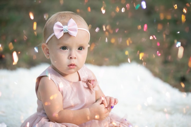 Une drôle de petite fille dans un confetti lumineux L'enfant fête un an Beau bébé