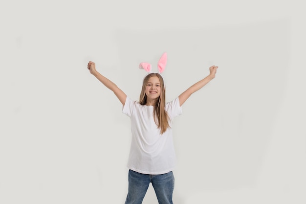 Drôle de petite fille dans un T-shirt blanc avec des oreilles de lapin isolé sur fond blanc