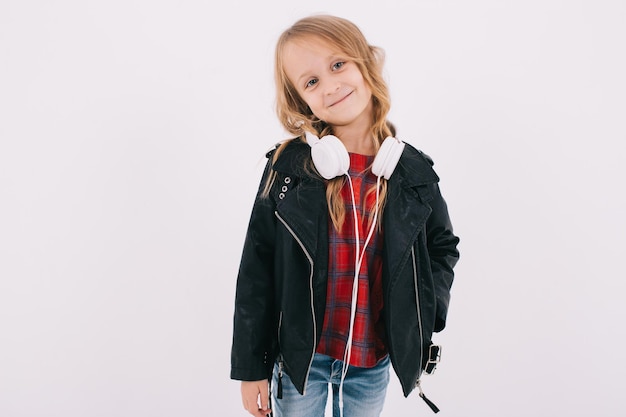 Drôle de petite fille dans une veste en cuir écoute de la musique rock dans les écouteurs