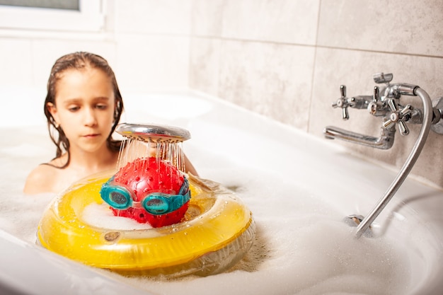 Drôle de petite fille douche une tête faite d'une balle et de lunettes de natation