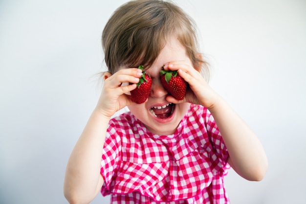 Drôle petite fille jouant avec des fraises