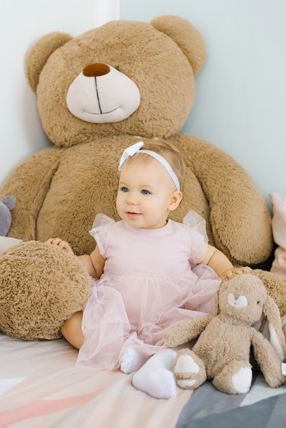 drôle de petite fille mignonne d'un an, assise sur le lit le matin avec un arc sur la tête