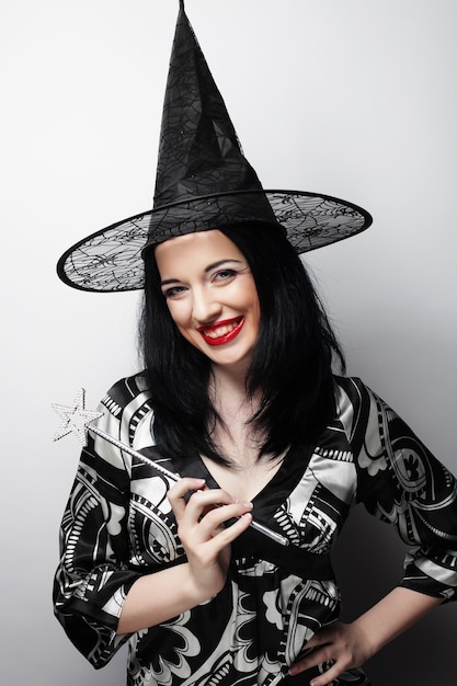 Drôle de sorcière. Jeune femme heureuse avec chapeau de canival. Prise de vue en studio.