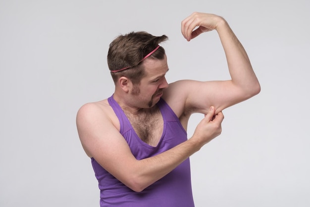 Photo drôle de sportif faible faisant de l'exercice en regardant sur ses biceps