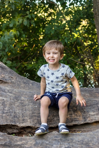 drôle tout-petit bébé garçon souriant sur l'arbre mignon petit enfant s'amusant assis dans le parc