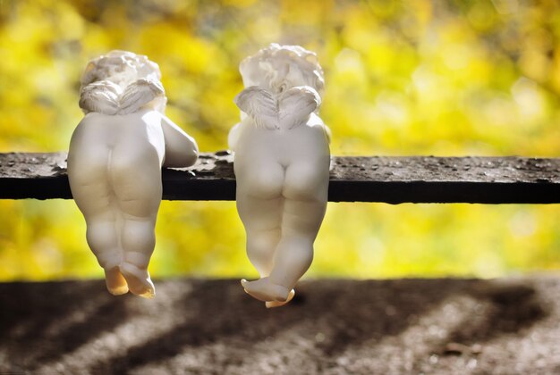 De drôles d'anges en céramique blanche avec de petites ailes sont en vue arrière dans le parc d'automne.