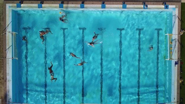 Drone aérien vue de dessus de personnes en compétition dans le water-polo dans une piscine d'eau turquoise