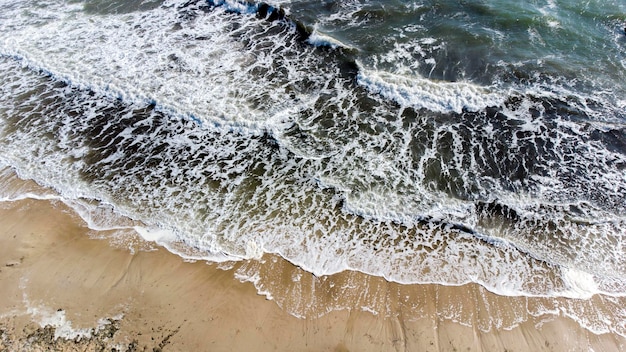 Drone aérien vue vol au-dessus des vagues de la mer qui roulent sur le rivage sablonneux