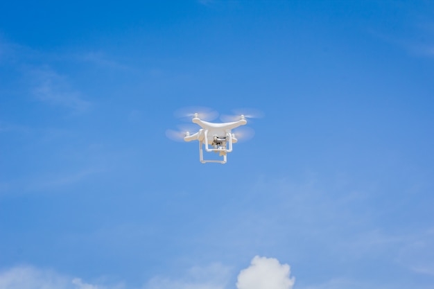 Drone avec caméra volant sur le ciel bleu et le fond des nuages