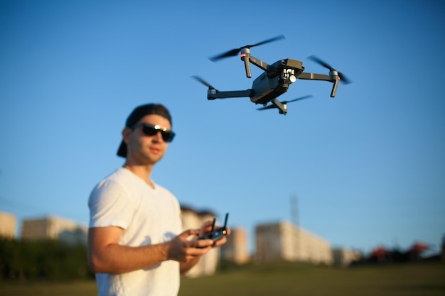 Un drone compact plane devant l'homme avec une télécommande dans les mains Le quadricoptère vole près du pilote