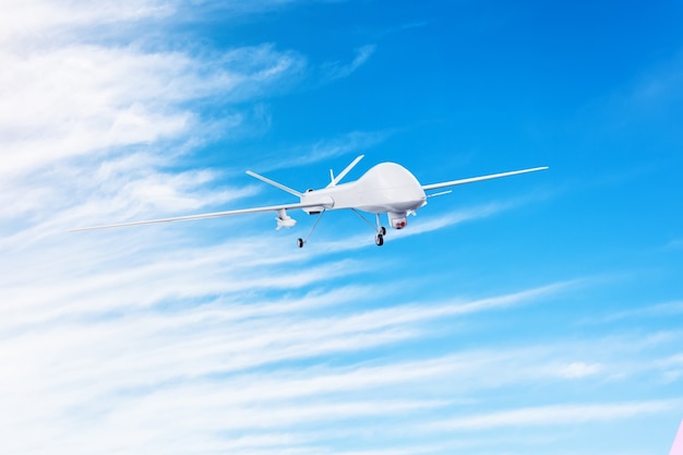 Un drone militaire sans pilote avec des missiles armés vole dans le ciel.