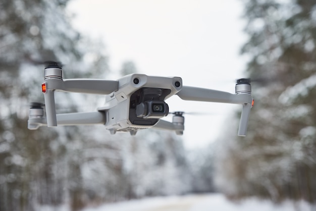 Drone quadcopter avec caméra volant dans la forêt d'hiver