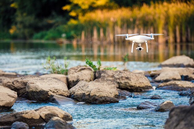 Drone quadricoptère volant avec une caméra au-dessus d&#39;un lac.