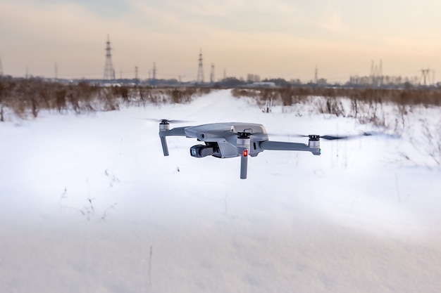 Drone quadrirotor survolant un champ enneigé en hiver