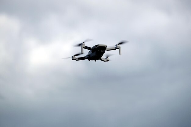 Un drone à quatre moteurs avec une caméra vole dans le ciel nuageux et orageux.