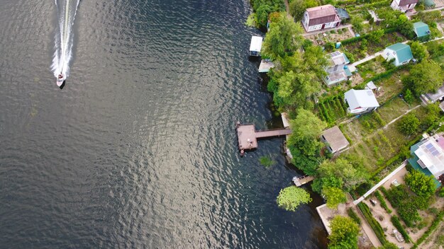 Drone survolent la rivière ondulante de couleur bleue entourée d'un village local avec divers bâtiments