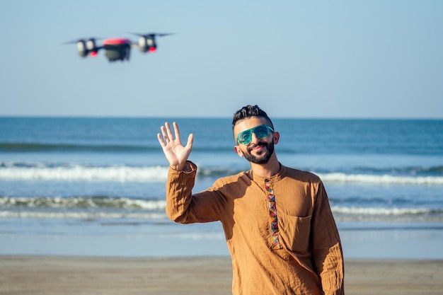 Drone télécommande homme arabe opérant un contrôleur d'hélicoptère sans contact par les mains par la mer