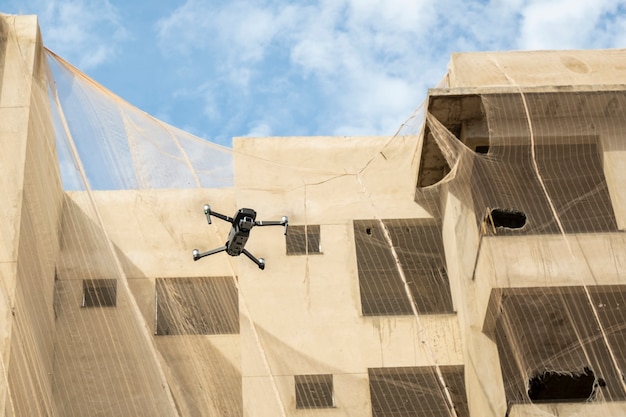 Un drone volant à côté d'un bâtiment en construction.