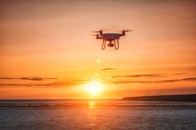 Drone volant sur fond de coucher de soleil sur la mer