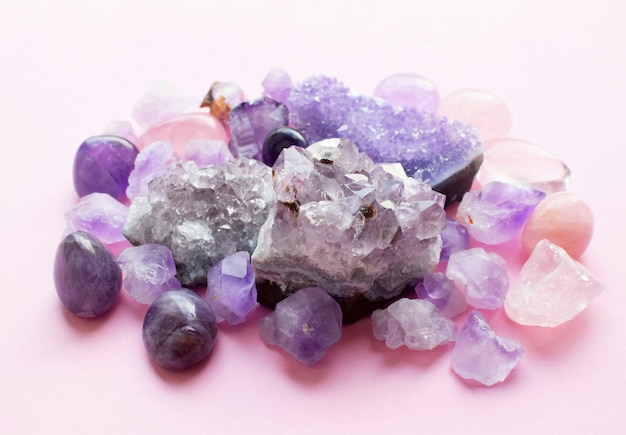Photo druses et cristaux d'améthyste et de quartz rose. de belles pierres semi-précieuses reposent sur la table. vue de dessus.