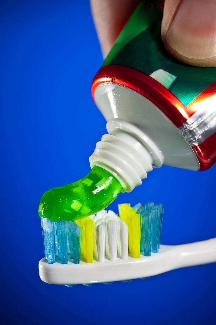Photo du dentifrice pressé sur une brosse à dents sur un fond bleu foncé