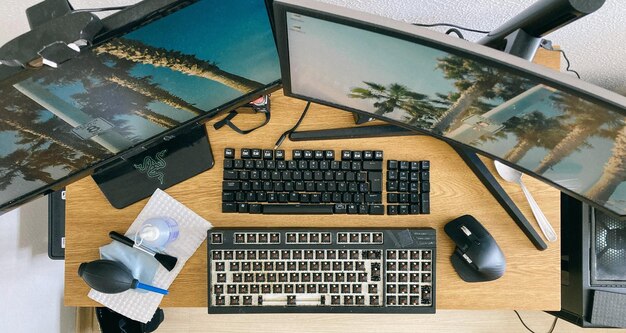 Photo du dessus du bureau avec plusieurs moniteurs et clavier avec suppression des touches pour le nettoyage photo