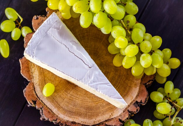 Du fromage brie et des raisins blancs frais sur une planche de bois