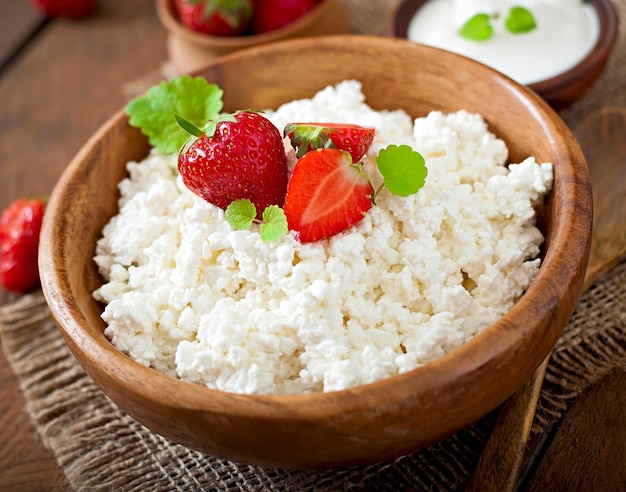 Du fromage cottage avec des fraises dans un bol en bois