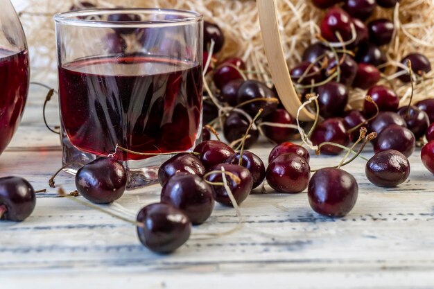 du jus de cerise ou du vin sur une table en bois un décanteur et un verre de jus