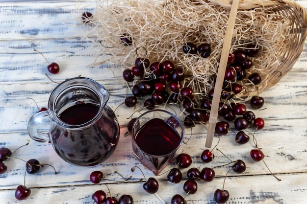 du jus de cerise ou du vin sur une table en bois un décanteur et un verre de jus