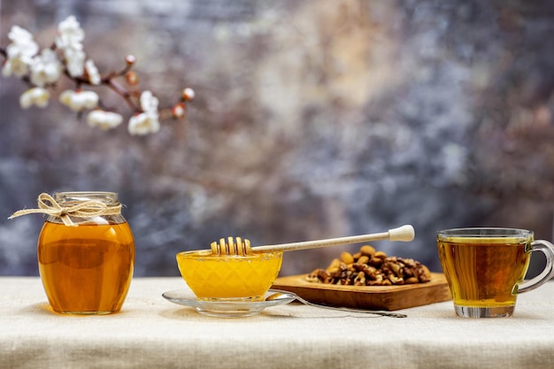 Du miel dans un pot et des noix sur une table en bois.