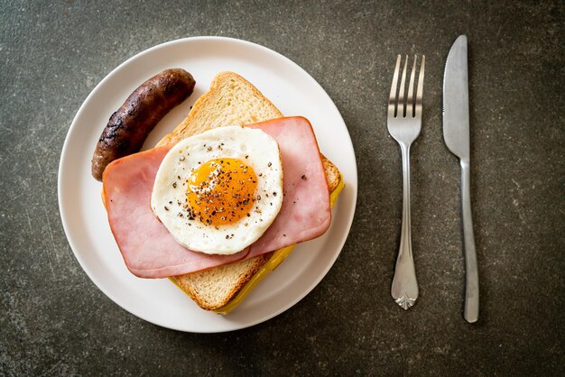 Photo du pain, du fromage grillé, du jambon et des œufs frits avec de la saucisse de porc