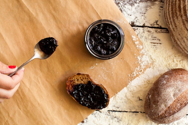 du pain frais croustillant est sur la table saupoudré de farine et tranche de pain avec une délicieuse confiture de baies