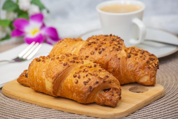 Du pain frais parfumé avec du café et une belle fleur est un bon petit déjeuner pour le corps sur la table.