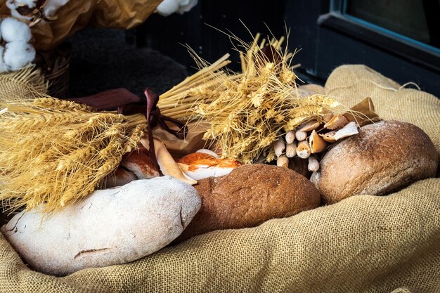 Photo du pain noir de blé fraîchement cuit sur un tissu de lin dans une boîte avec un bouquet de seigle