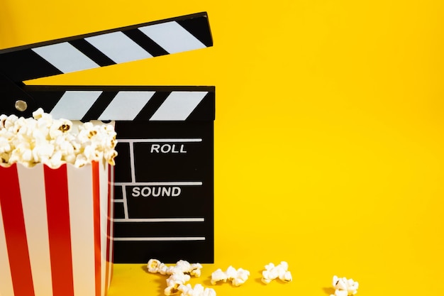 du pop-corn avec du clapperboard de film sur un fond jaune