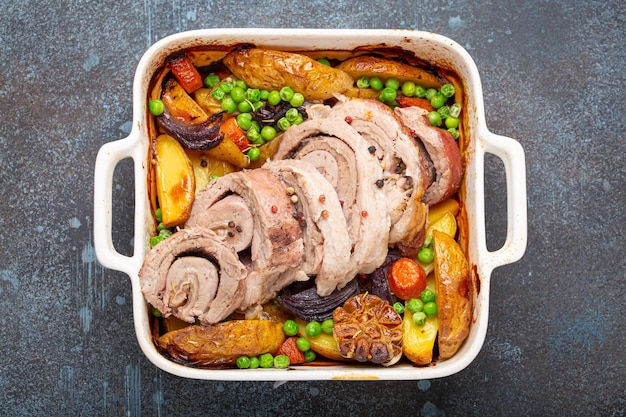 Photo du porc en tranches roulées rôti dans un plat de casserole blanche avec