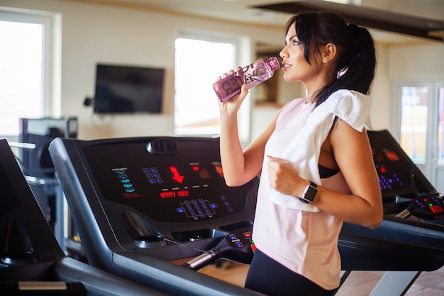 du sport et mode de vie sain. Femme séduisante jeune de remise en forme en cours d'exécution sur tapis roulant, portant des vêtements de sport blancs. Femme sportive en bonne santé, faire des exercices cardio sur tapis roulant