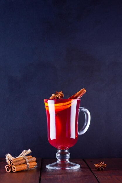 Du vin chaud avec des bâtons de cannelle sur fond sombre Un verre de vin chaud et des épices