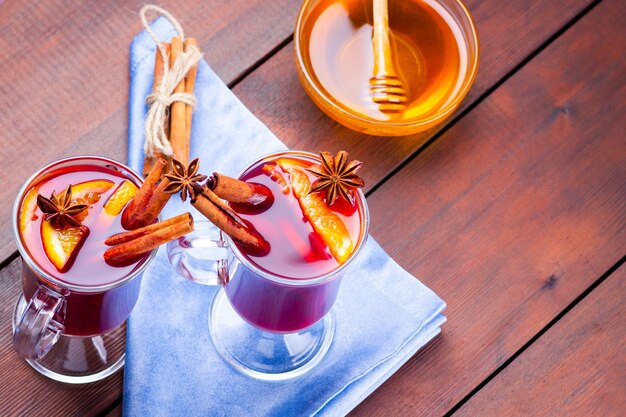 Du vin chaud avec des épices et du miel sur un fond en bois deux verres de vin chaud rouge sur une serviette bleue